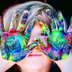Vibrant close-up of a child's hands covered in colorful paint, expressing creativity and fun.